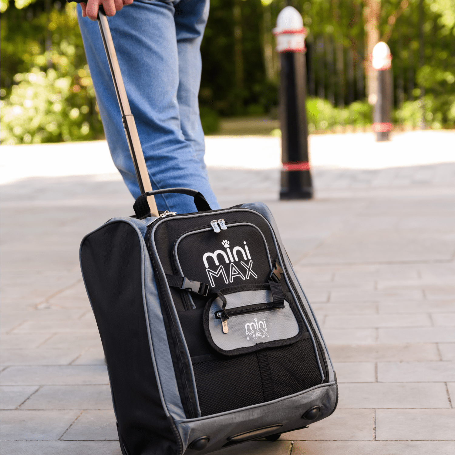Aerolite MiniMAX black suitcase being rolled on a pavement, showcasing its lightweight design and telescopic handle.