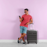 Man with Aerolite suitcase against pink wall