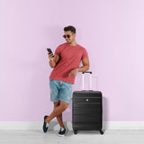 Man with black Aerolite suitcase against pink wall