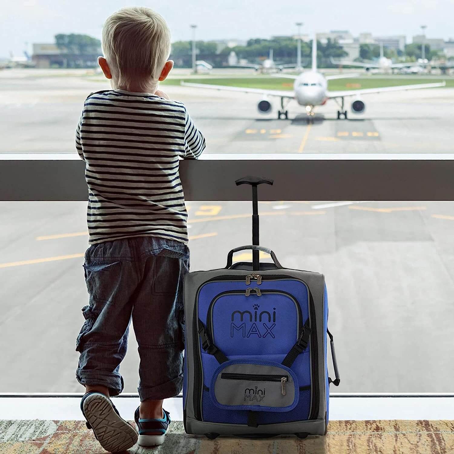 Child standing at an airport window with Aerolite MiniMAX blue suitcase, showcasing its kid-friendly design.