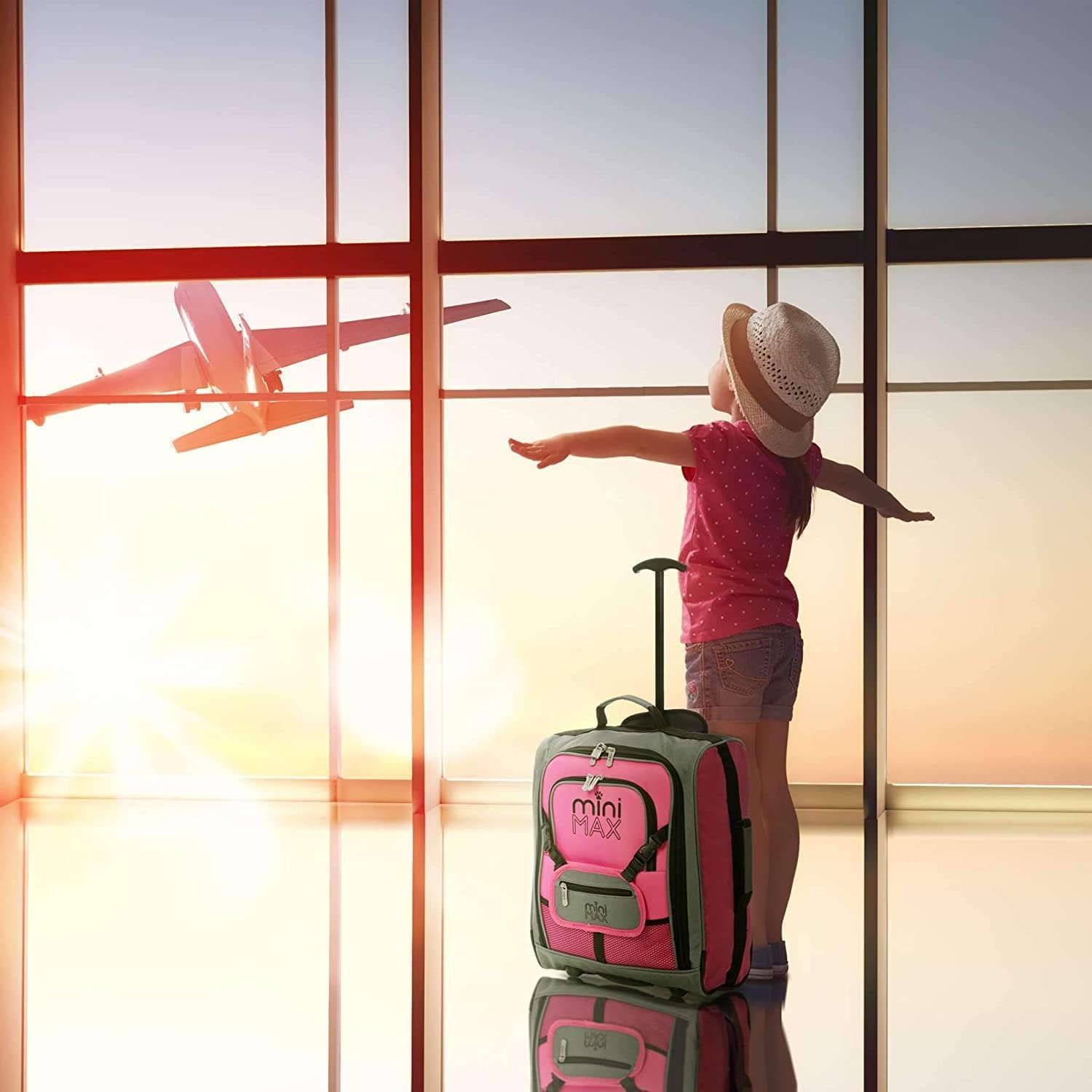 Child at an airport window with Aerolite MiniMAX pink suitcase, highlighting its kid-friendly and travel-ready design.