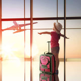 Child at an airport window with Aerolite MiniMAX pink suitcase, highlighting its kid-friendly and travel-ready design.