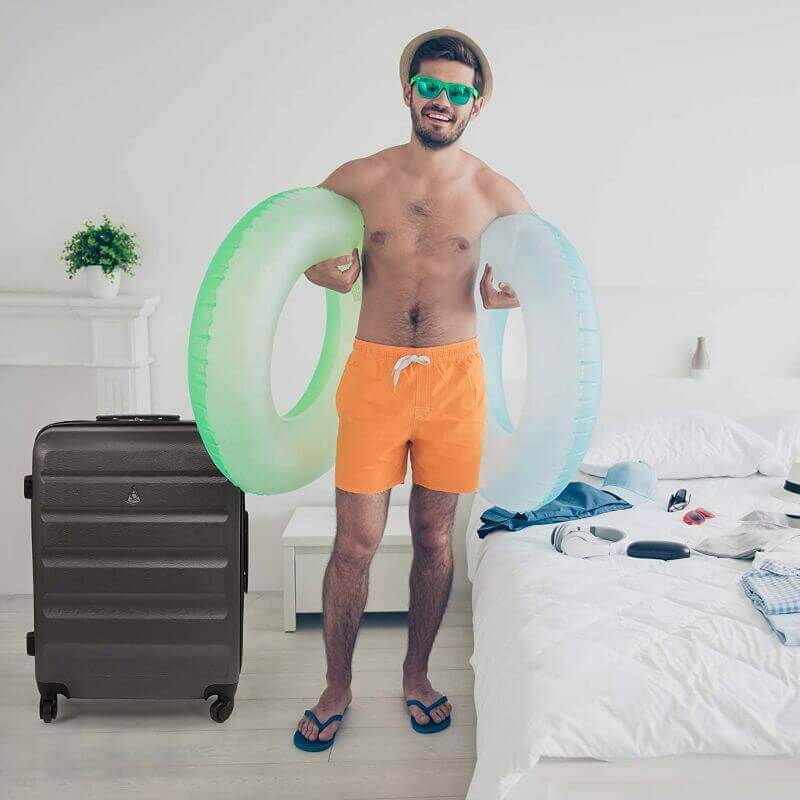 Man with beach gear and Aerolite suitcase in room